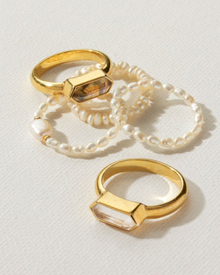 Assortment of gold gemstone rings next to pearl stretch rings by Luna Norte Jewelry.
