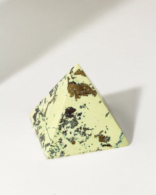 Pyramidal curio showing bright hue of serpentine swirled with the reflective properties of pyrite on a white background. 
