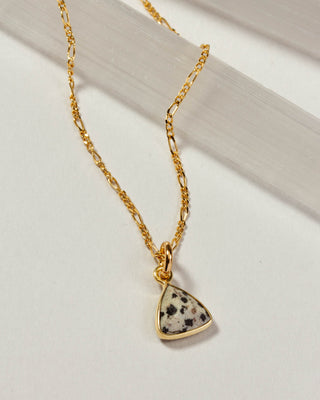 Close up of Dalmatian Jasper Bermuda Triangle Dainty Collar Necklace with a 14 Karat Gold Plated Brass chain laying on a white background.