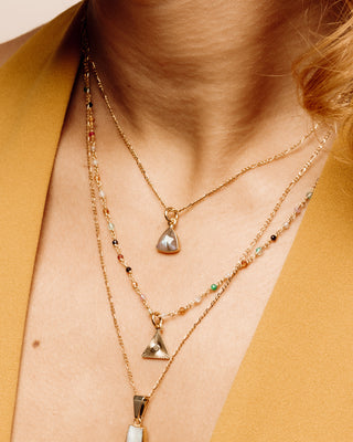 Closeup of woman's neckline wearing Labradorite Bermuda Triangle Dainty Collar Necklace layered with two other necklaces.