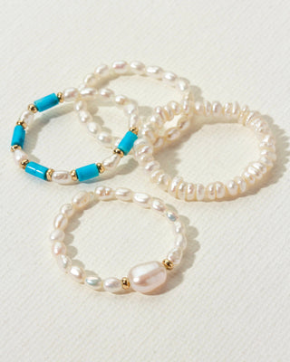 Collection of four cultured pearl stretch rings, one with turquoise by Luna Norte Jewelry.