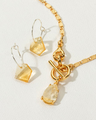 Silver geometric citrine earrings next to gold toggle clasp citrine pendant necklace, November's birthstone.