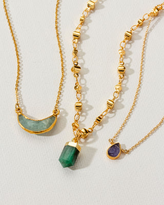 Three gold necklaces with green amazonite, emerald, and sapphire pendants.