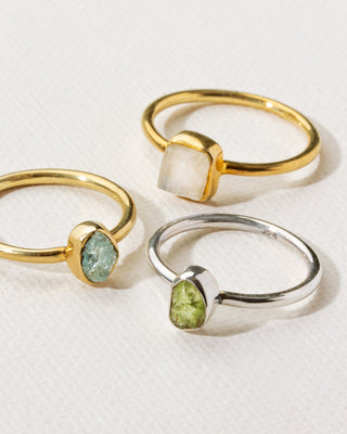 Collection of 3 gold and silver gemstone rings with moonstone, peridot, and aquamarine.