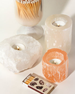 Collection of white quartz and orange selenite candle holders with candles and matches, by Luna Norte.