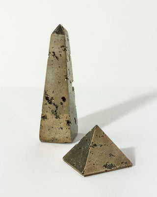 Standing pyrite obelisk and pyrite pyramid siting on a table, by Luna Norte.