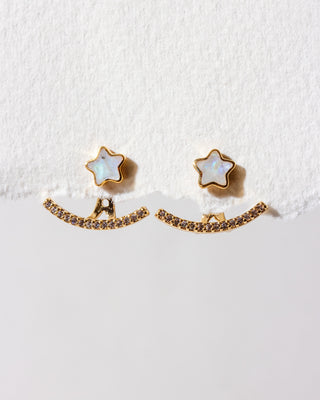 A pair of earrings featuring a post front back design with a star-shaped rainbow moonstone stud and a sparkling clear cz cluster ear jacket in gold plating.