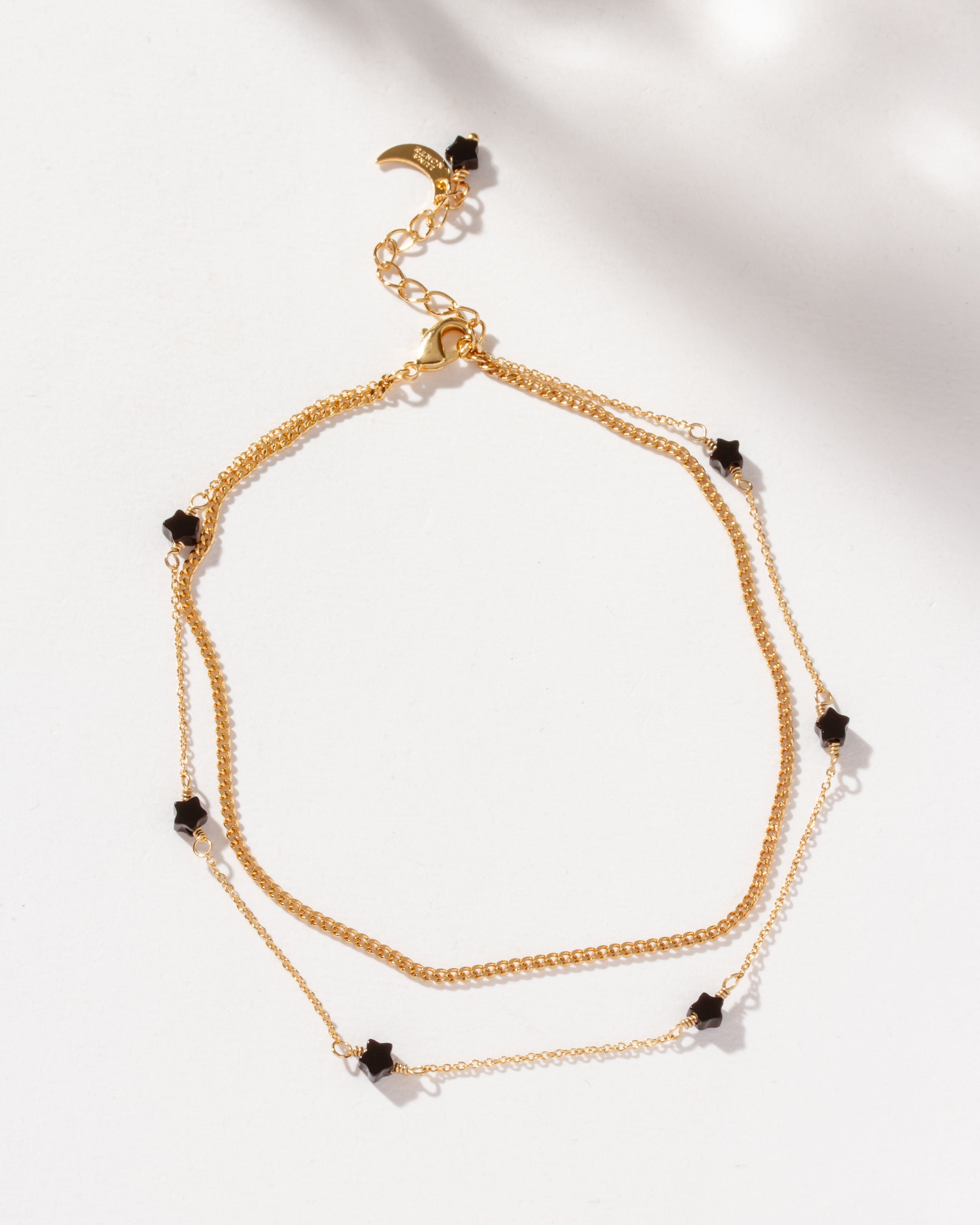 Gold Constellation Anklet with star-shaped onyx beads on a layered chain.