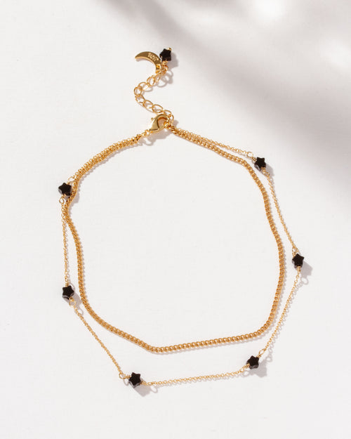 Gold Constellation Anklet with star-shaped onyx beads on a layered chain.