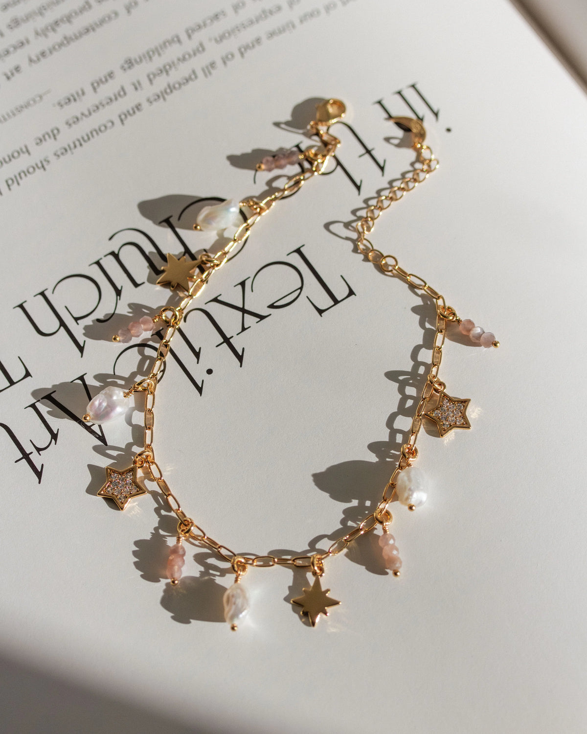 Gold plated chain with many charms on a book page.