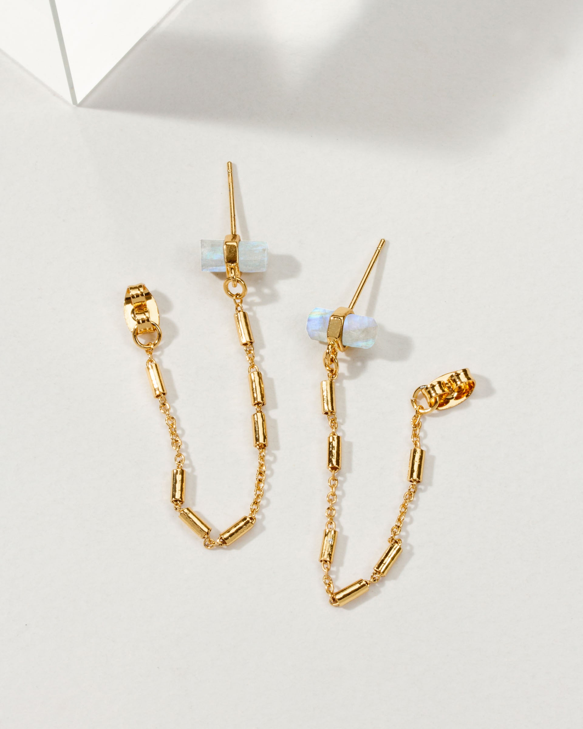 Pair of gold earrings with a front-to-back design with chain accents and moonstones.