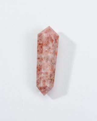 A double-pointed sunstone crystal with golden-peach tones on a white background.
