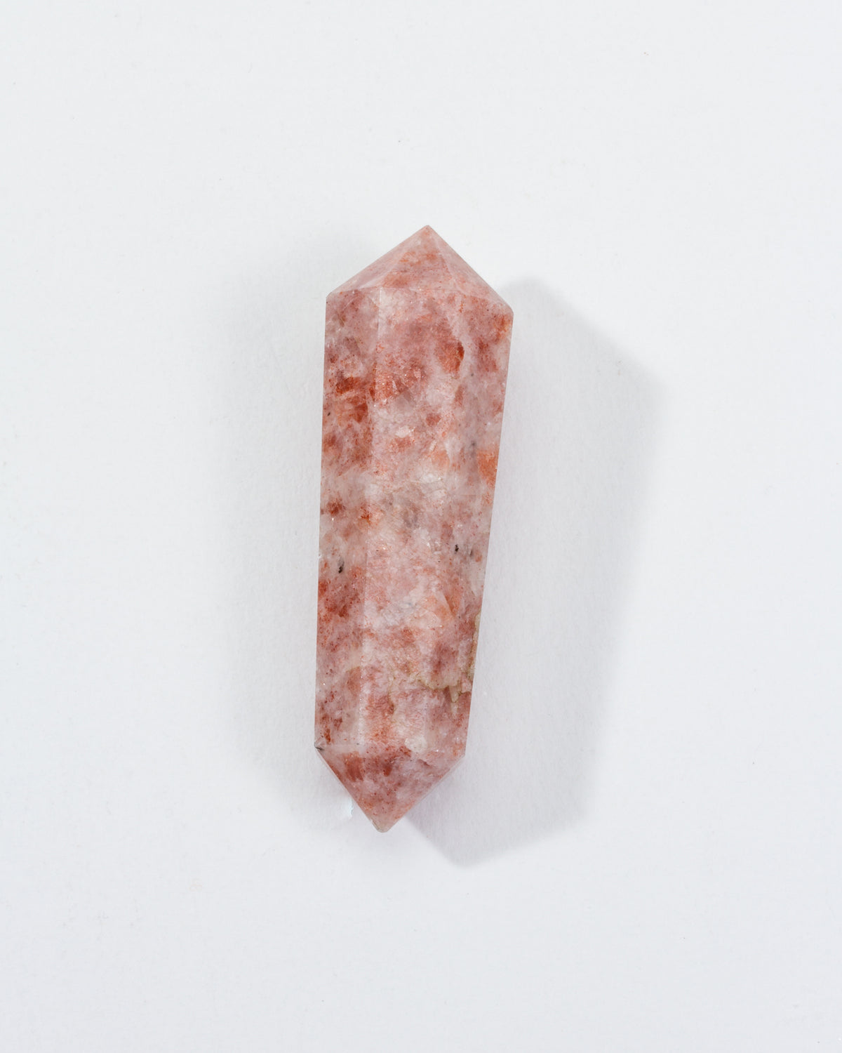 A double-pointed sunstone crystal with golden-peach tones on a white background.