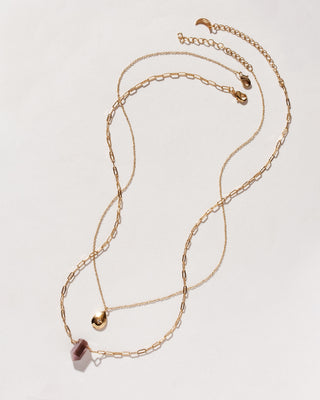 Gold chain necklaces, one with a coffee moonstone pendant, and one with a gold teardrop charm on a white background