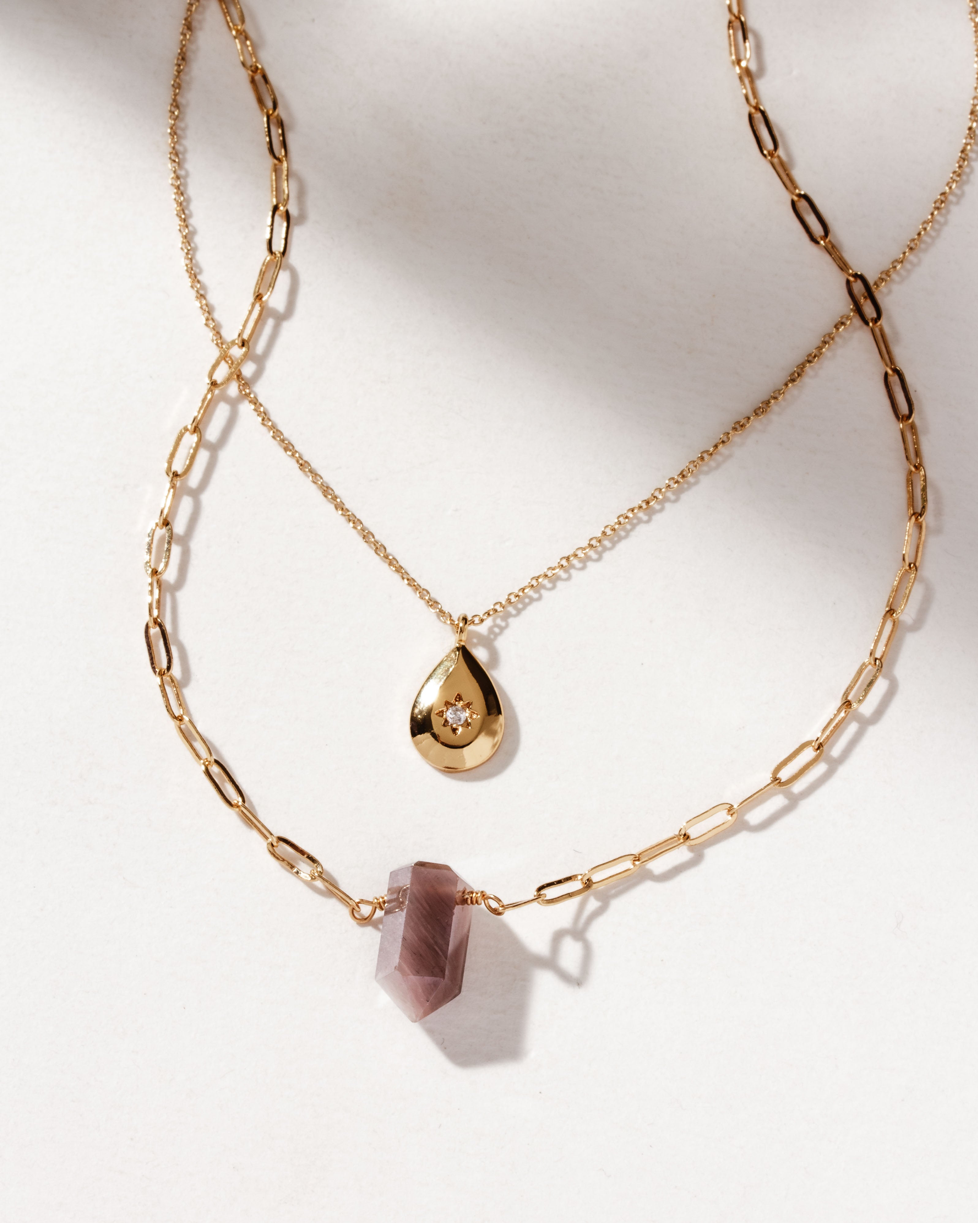 Two gold necklaces, one with gold teardrop, and the other with coffee moonstone pendant
