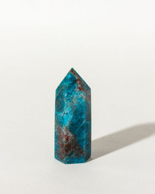 A faceted, geometrically shaped blue Apatite gemstone tower against a white background.