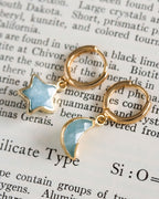 Pair of mismatched gold huggie hoop earrings with aquamarine star and moon charms