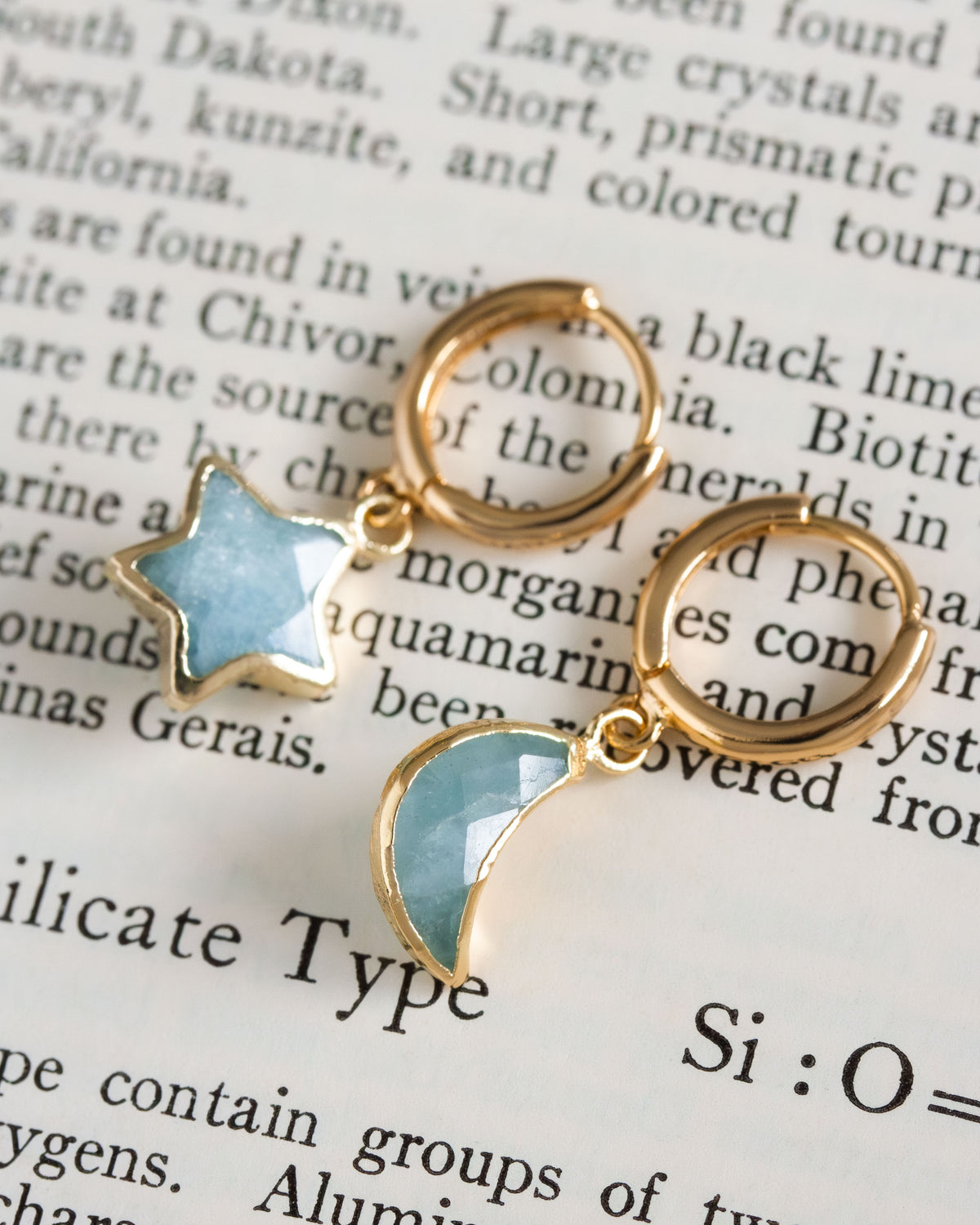 Pair of mismatched gold huggie hoop earrings with aquamarine star and moon charms
