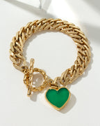Gold chain bracelet with a green gemstone heart pendant and toggle closure.
