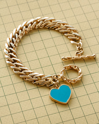 A gold-toned chunky chain bracelet with a toggle clasp and a heart-shaped turquoise charm.