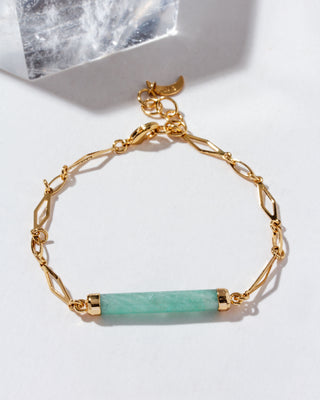 Gold bracelet with a long cylindrical aquamarine gemstone on a white background
