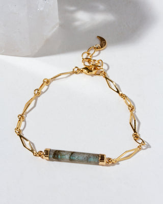 Gold bracelet with a long cylindrical labradorite gemstone on a white background