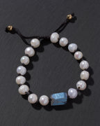 Pearl bracelet with a blue stone on a dark surface