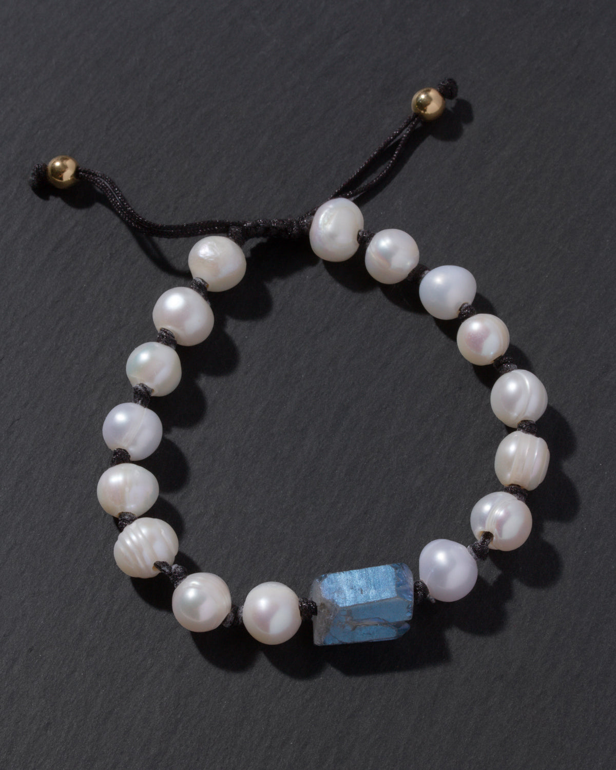 Pearl bracelet with a blue stone on a dark surface
