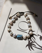 Pearl bracelet with a blue stone on a white surface