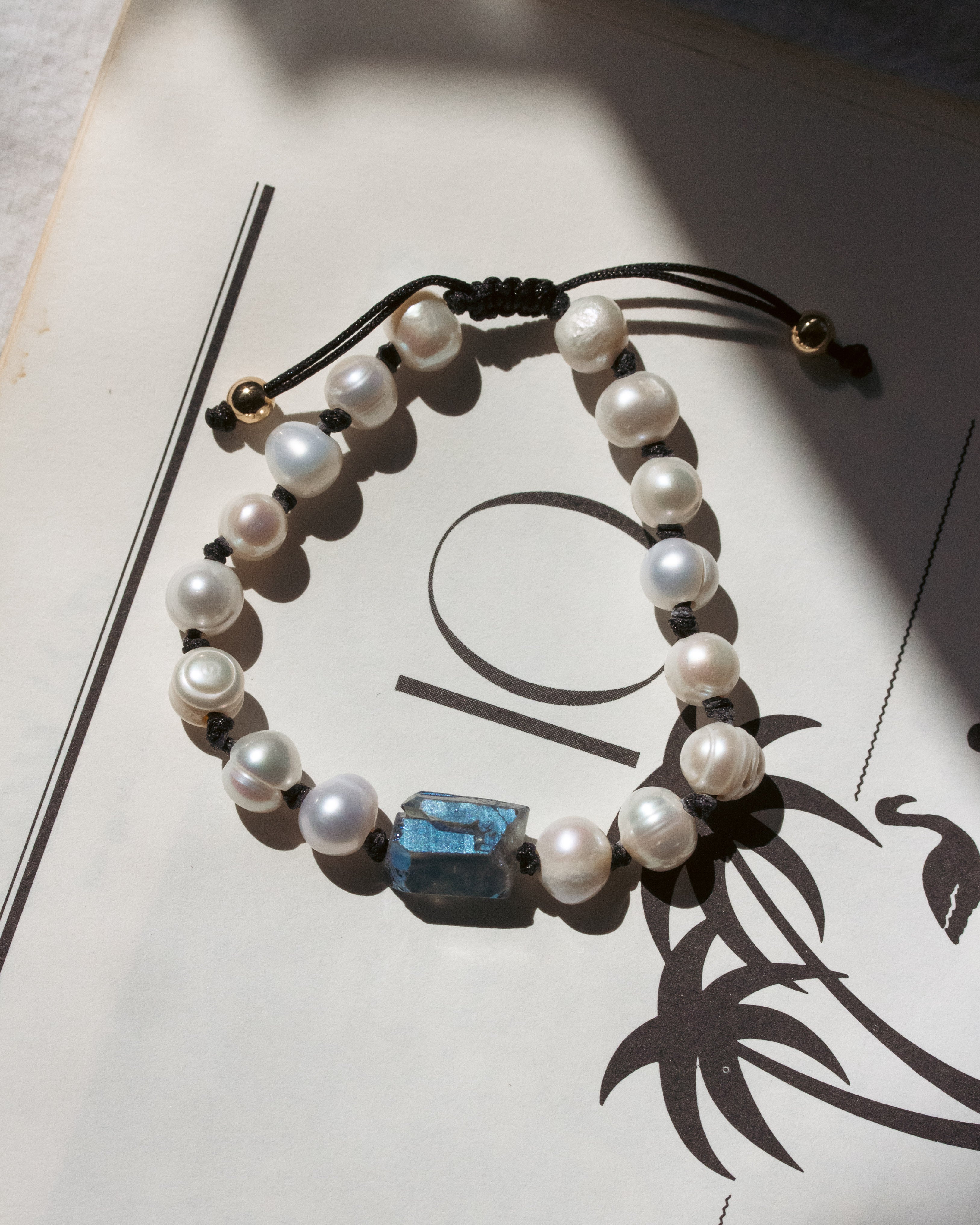 Pearl bracelet with a blue stone on a white surface