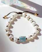 Pearl bracelet with a blue crystal bead on a white surface