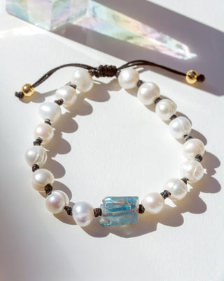 Pearl bracelet with a blue crystal bead on a white surface