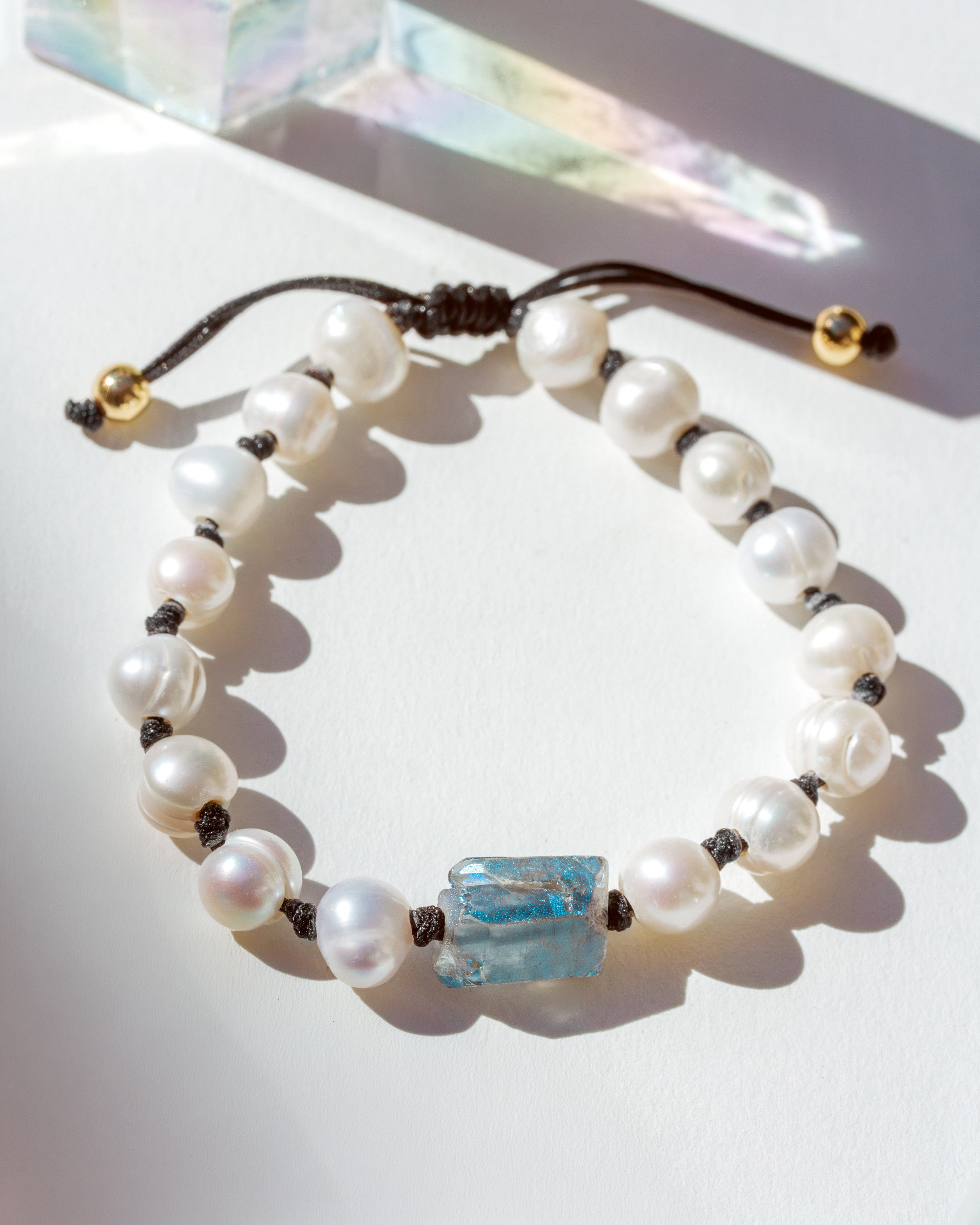 Pearl bracelet with a blue crystal bead on a white surface