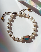 Pearl bracelet with a colorful stone on a white surface
