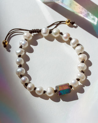 Pearl bracelet with a colorful stone on a white surface