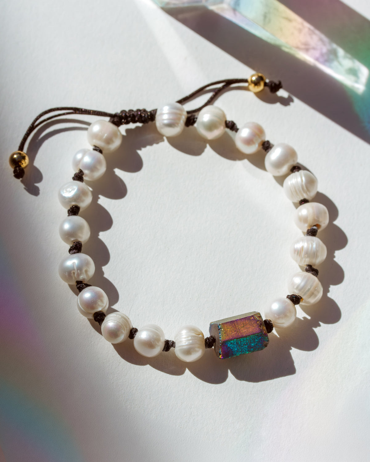 Pearl bracelet with a colorful stone on a white surface