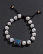 Pearl bracelet with a colorful gemstone on a dark background
