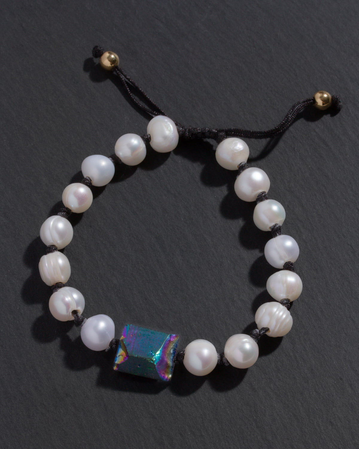 Pearl bracelet with a colorful gemstone on a dark background
