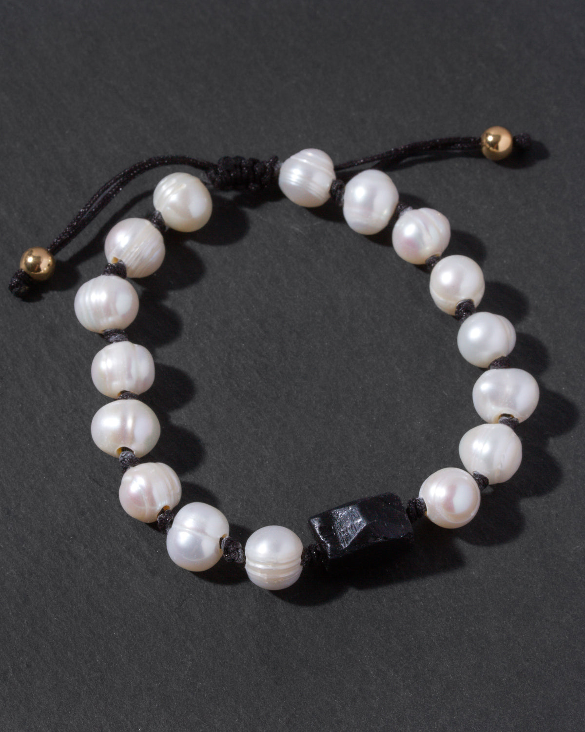 Pearl bracelet with black tourmaline bead on a dark background