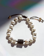 Pearl bracelet with a black tourmaline stone bead on a light background