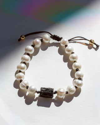 Pearl bracelet with a black tourmaline stone bead on a light background