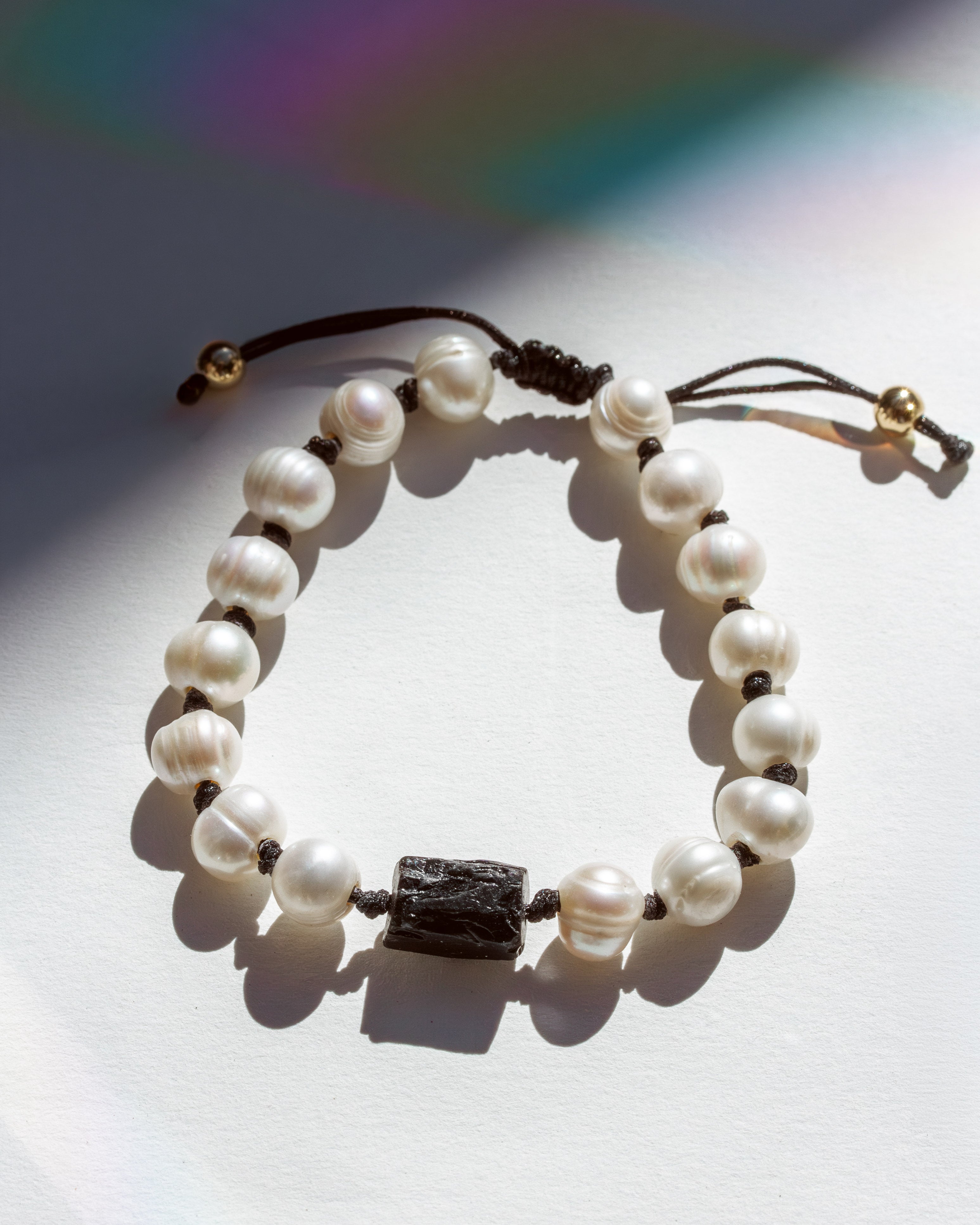 Pearl bracelet with a black tourmaline stone bead on a light background