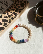 Colorful beaded bracelet on a white surface with a leopard print book and black container