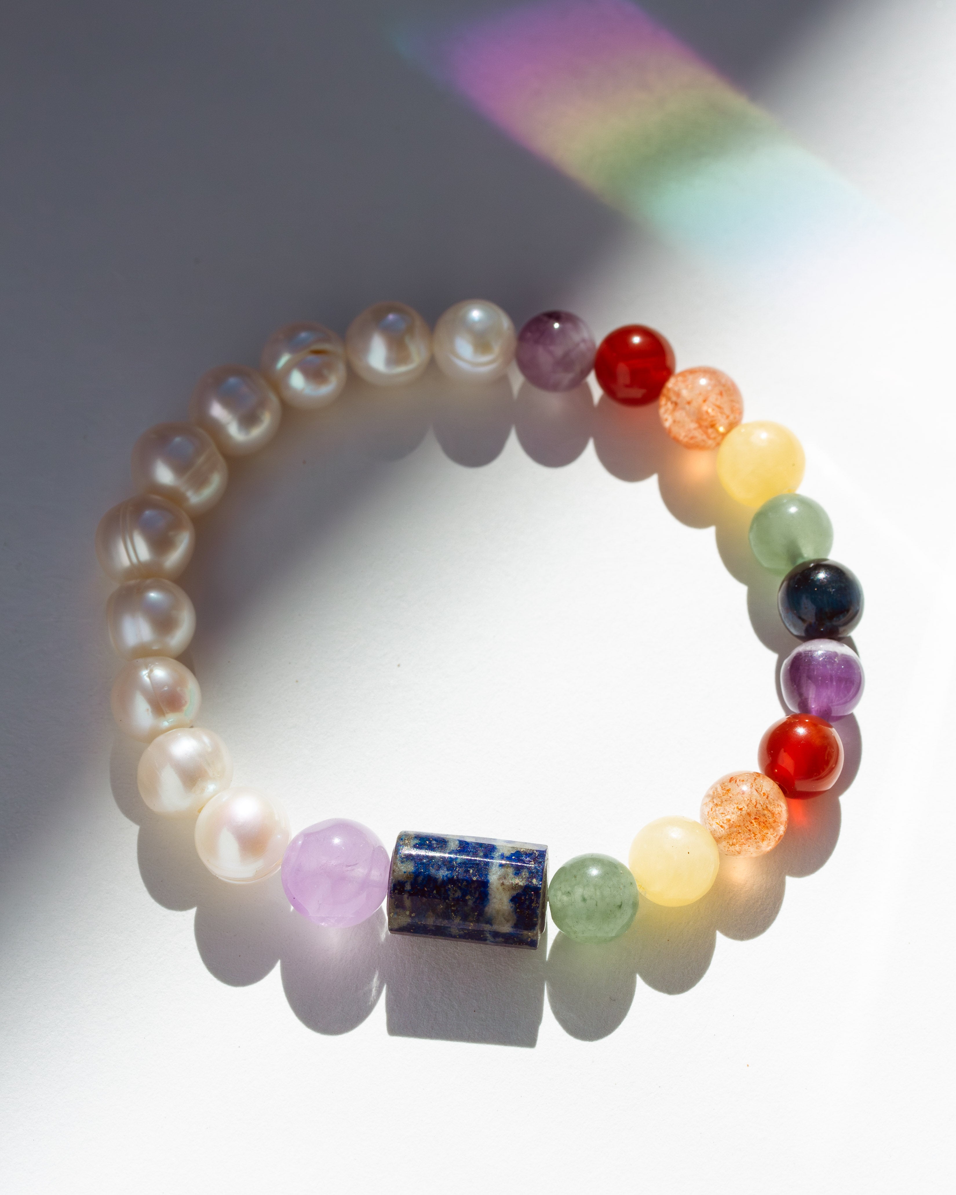 Multicolored beaded bracelet on a white background with rainbow light effect