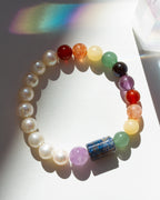 Multicolored beaded bracelet on a white surface with a rainbow shadow