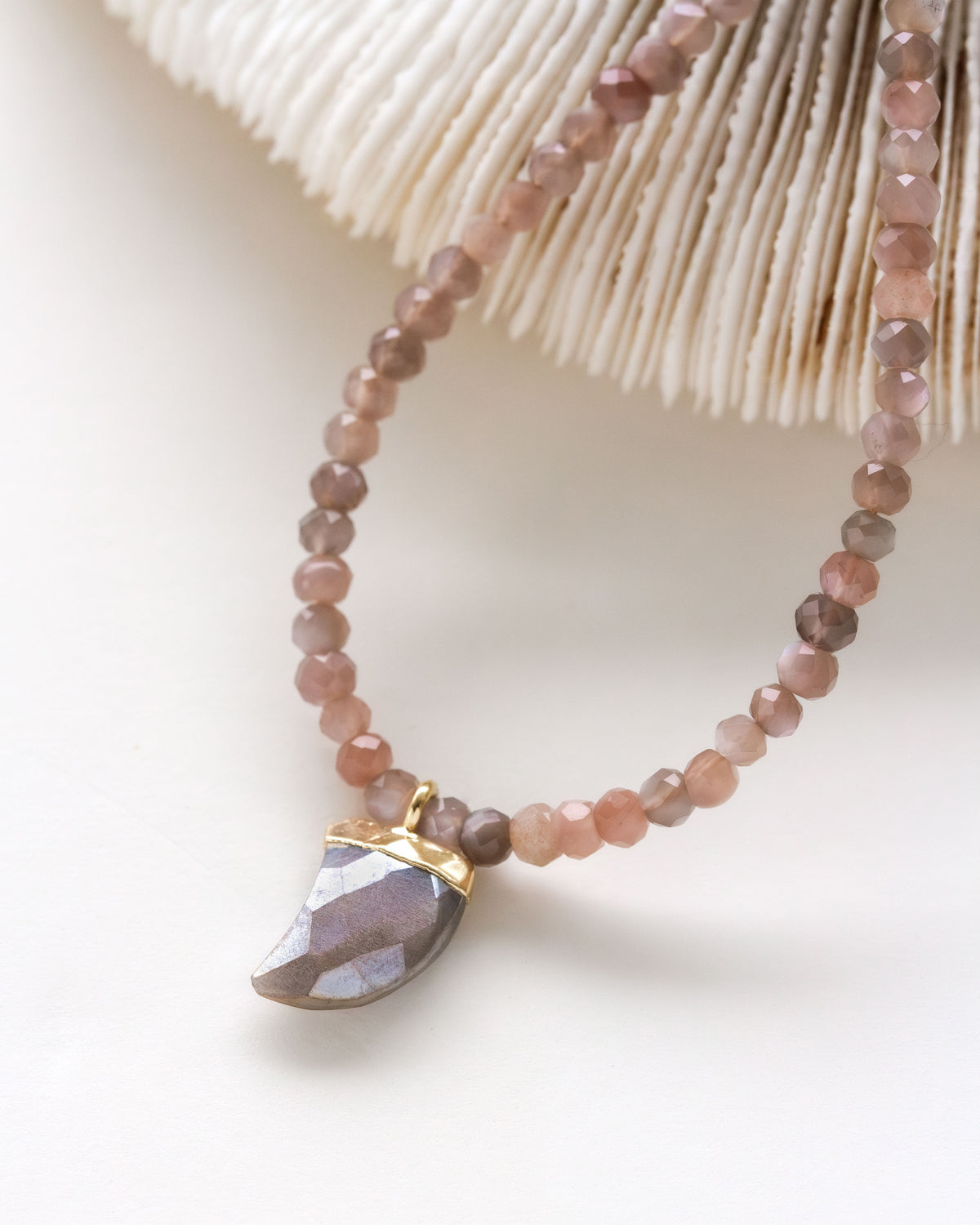 A collar-length necklace with shark tooth shaped coffee moonstone charm and beads.