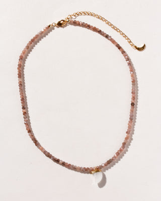 A collar-length necklace with coffee moonstone beads and a carved rainbow white moonstone shark-tooth shaped charm, displayed against a soft background.