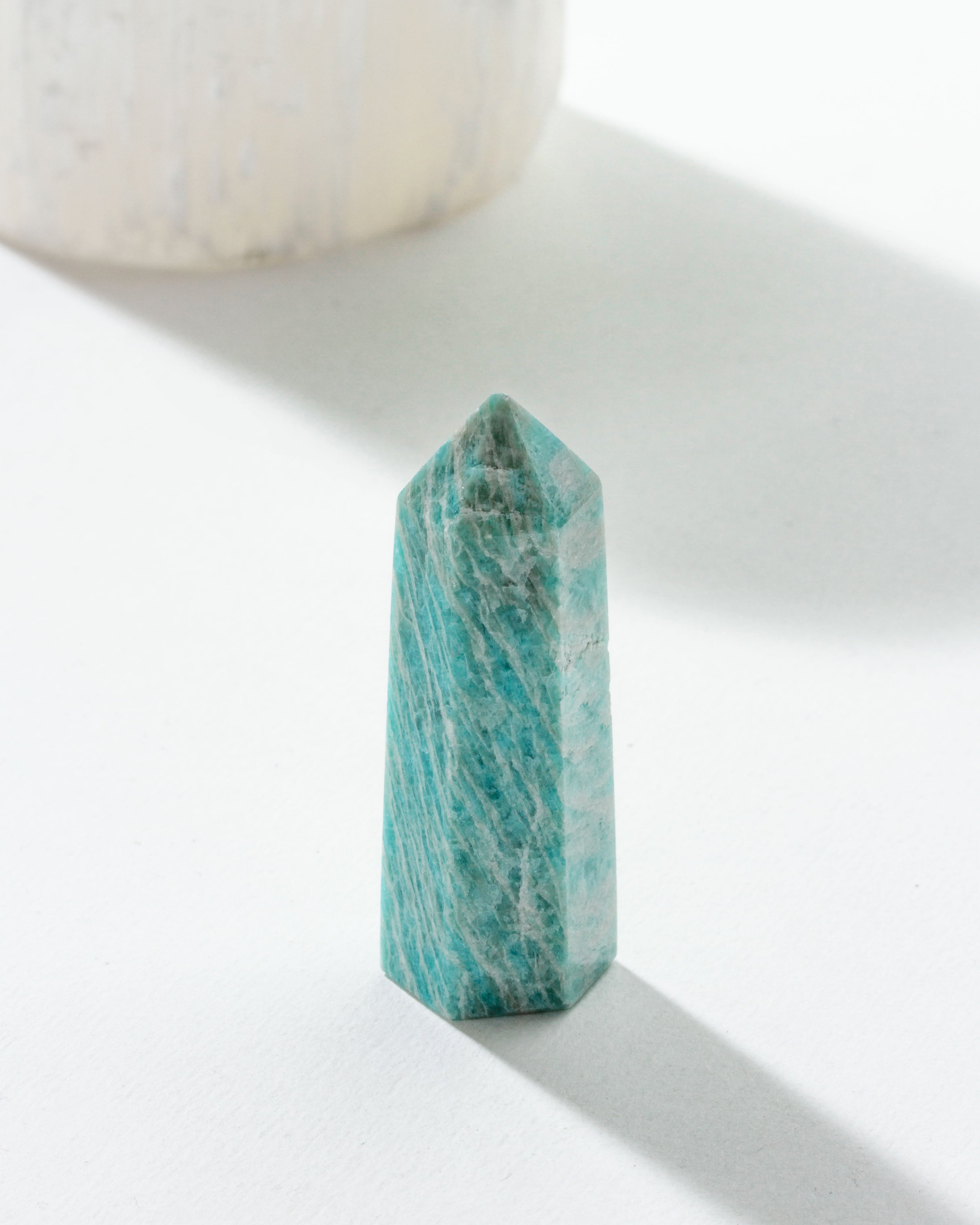 A striped Amazonite gemstone in a tower shape, displaying a blue-green pattern