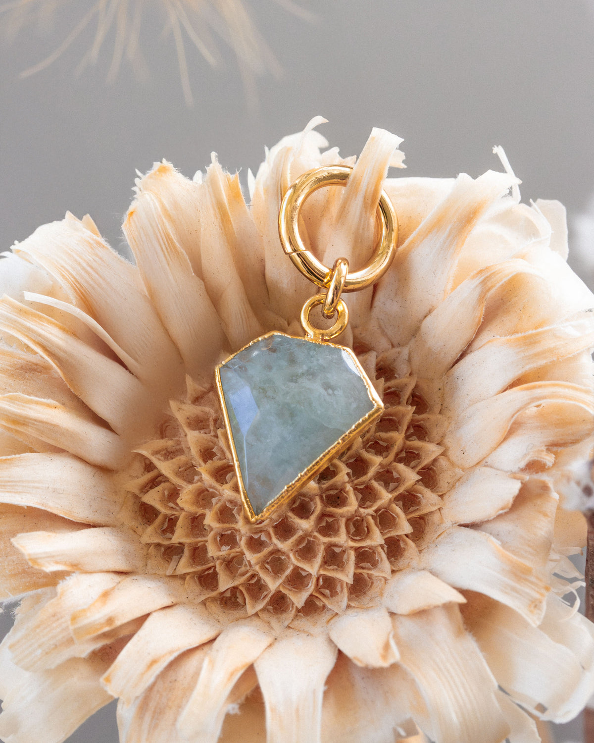 A gold interchangeable hoop earring charms with a faceted gemstone, resembling a diamond