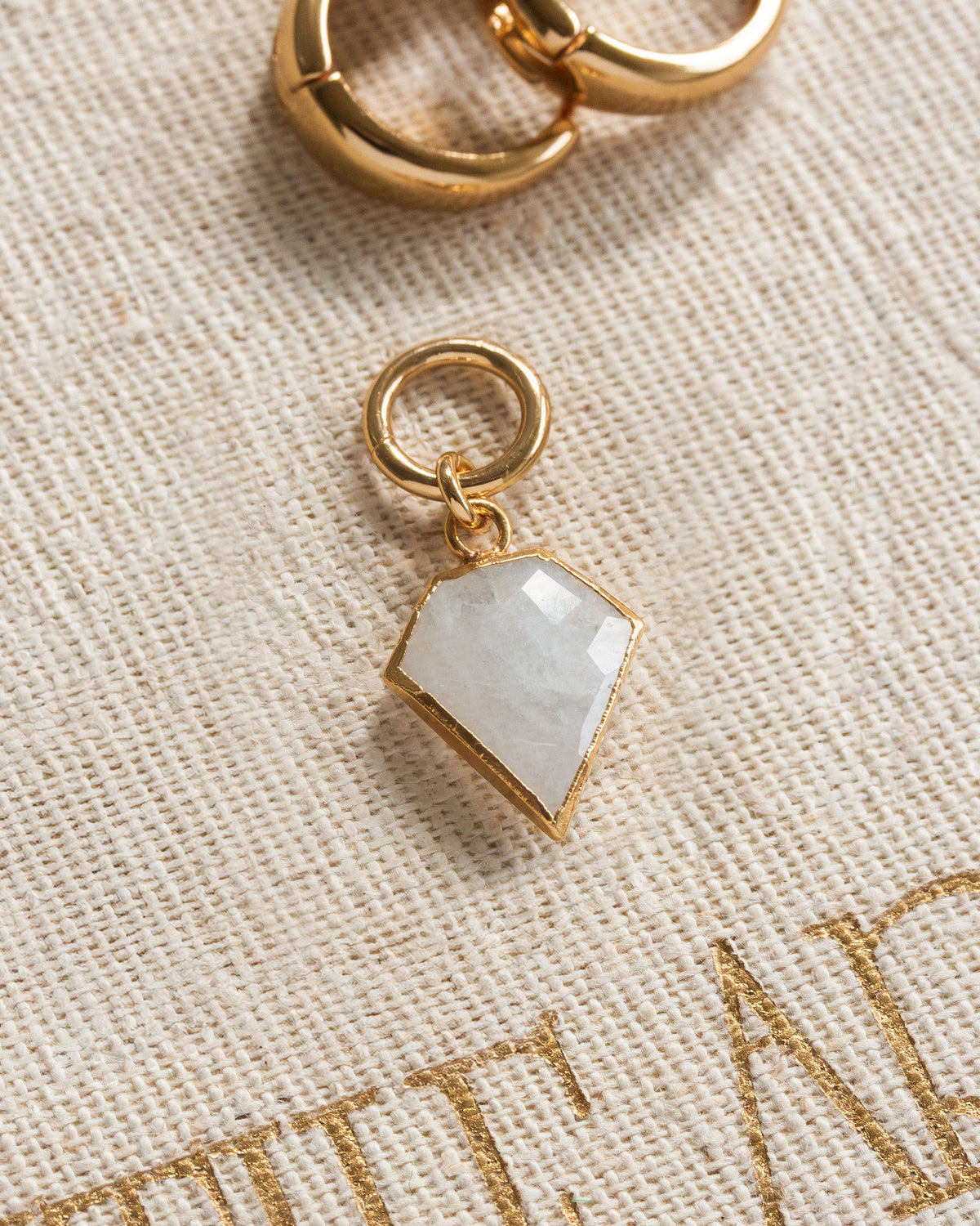 Pair of gold interchangeable hoop earring charms with a faceted moonstone, resembling a diamond